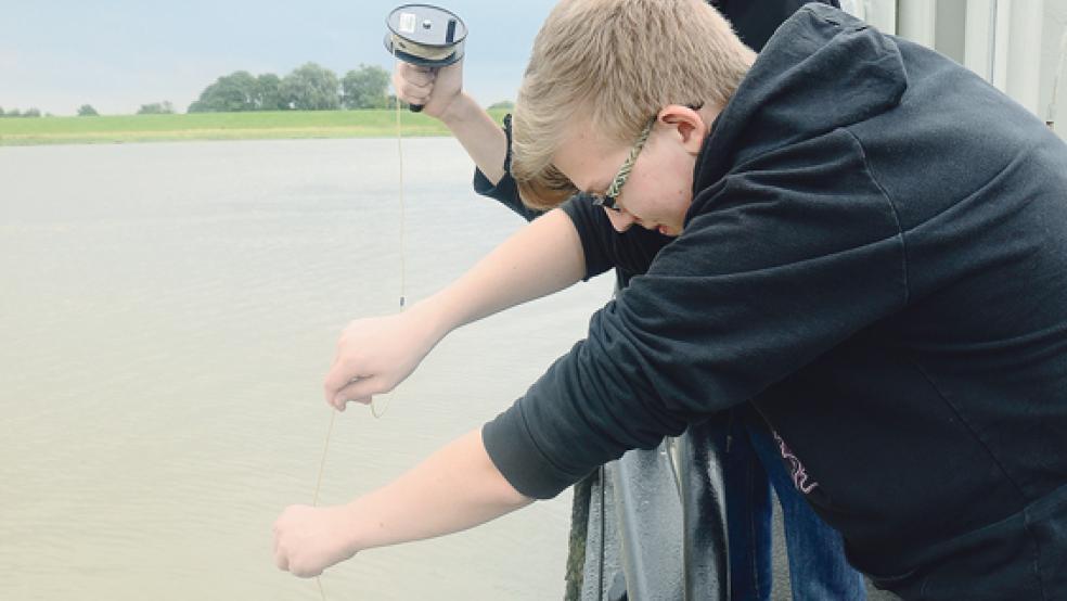 Matthis Simon (vorne) und Dominic de Vries erklärten, wie das Wasser entnommen wird (kleines Bild). Markierungen an dem Band zeigen an, welche Wassertiefe erreicht wird. © 