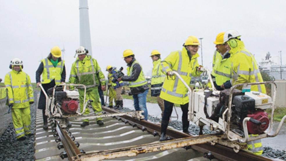 Fleur Graper-van Koolwijk (Provinzministerin von Groningen), Jan Mulder (Direktor Regio Noord-Oost von ProRail) und Marijke van Beek (Bürgermeisterin der Gemeinde Eemsmond) legten gestern zusammen die letzten Meter Gleis an der Borkumkade in Eemshaven. © Foto: Provinz Groningen