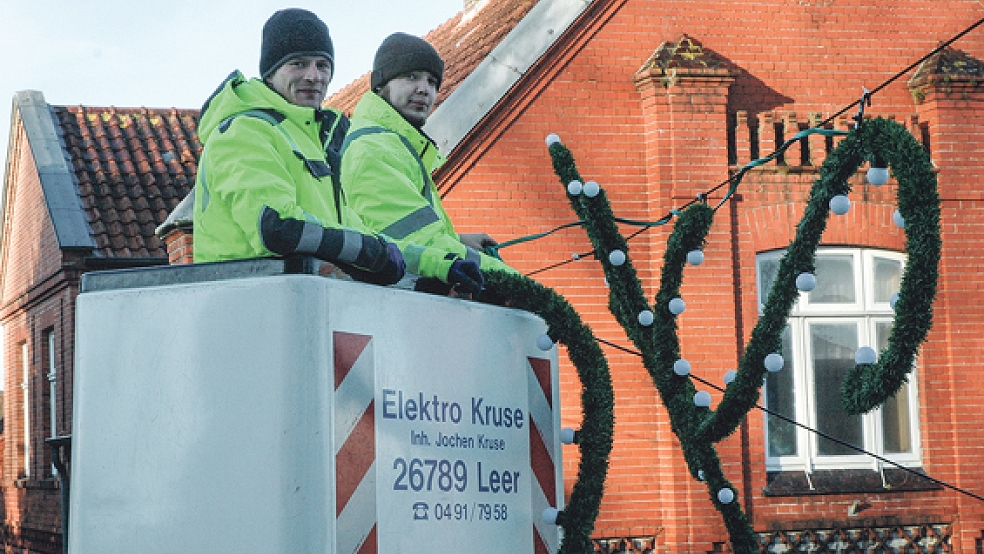 Mitarbeiter der Firma Elektro Kruse aus Leer montierten am Samstag die ersten Weihnachtsbeleuchtungen in Weener - wie hier über der Risiusstraße. © Foto: Szyska