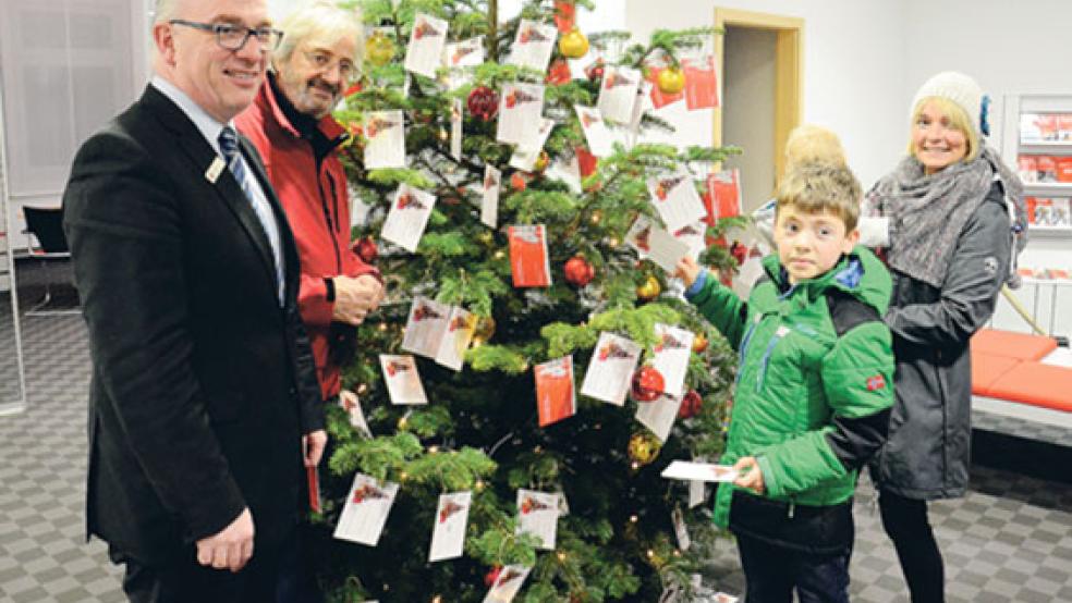 Joachim Tjabben von der Sparkasse und Volker Kraft freuten sich, als einige Kinderwünsche bereits nach wenigen Minuten von Hauke (10), Bente (1) und Mutter Kerstin Oosterheert (im Bild von links) vom Baum genommen wurden. © Foto: Muising