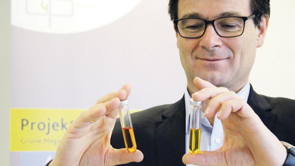 Ralf Riekenberg zeigt die Flüssigkeit aus gesättigter Sole, in der kleinste Kunststoffteilchen (Polymere) aufgelöst wurden. Darin lässt sich Strom speichern. © Foto: Diebels (EWE)