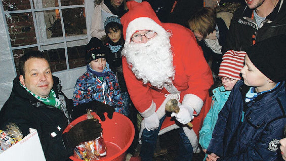 Wenn der Weihnachtsmann mit seiner Glocke klingelt, kommen die Kinder angerannt. Stefan Kuper, Vorsitzender des Ortsvereins (links), half beim Verteilen der Süßigkeiten. © Fotos: Kuper