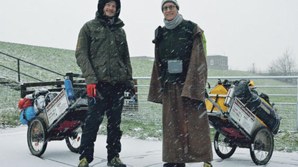 Von Weener aus ging es für Heiko Gärtner (links) und Franz von Bujor bei Schnee am Deich entlang nach Leer. Ihr Hab und Gut ziehen sie mithilfe zweier Handwagen hinter sich her. © 