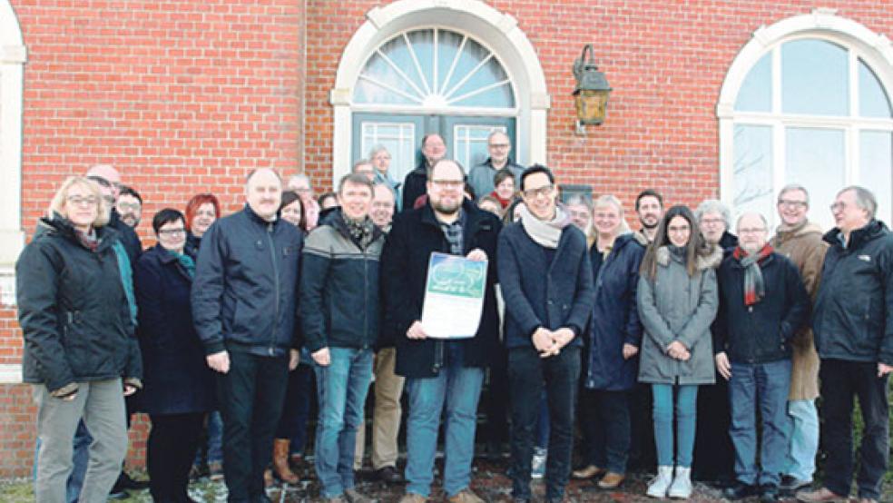 Vor dem Gemeindehaus in Holtgaste: Die Mitglieder der lutherischen Kirchenkreiskonferenz mit den stellvertretenden Super­intendenten Sven Grundmann und Wolfgang Ritter (vorne, von links) begrüßten Landesposaunenwart Hayo Bunger (mit Plakat des Landesposaunenfestes) und Klaus Motoki Tonn, Leiter der Kommunikation der Landeskirche. © Foto: Dübbel (Kirchenkreis)