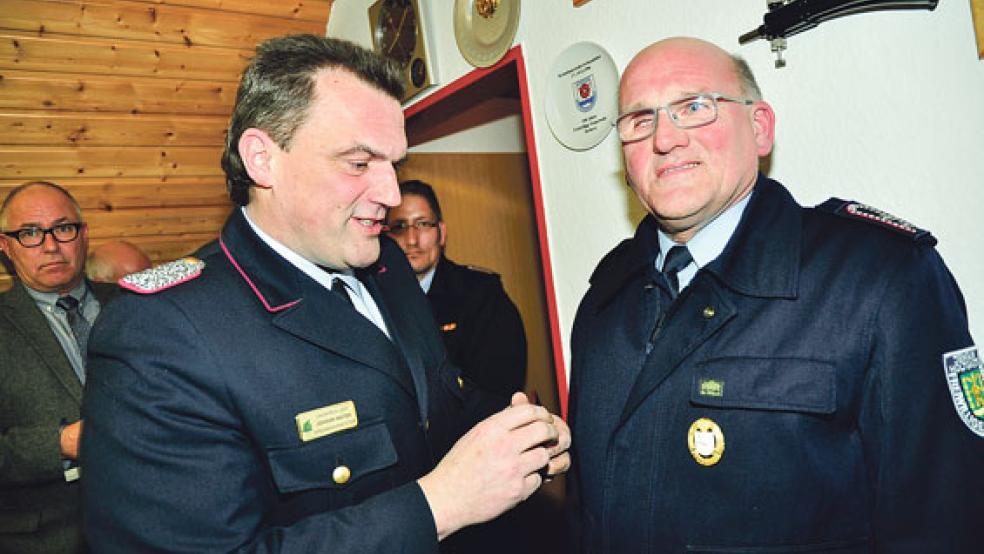 Kreisbrandmeister Johann Waten ehrt Bajo Leemhuis für sein 40-jähriges Engagement in der Freiwilligen Feuerwehr Holtgaste. Im Hintergrund Bürgermeister Hans-Peter Heikens (links).  © Foto: Wolters