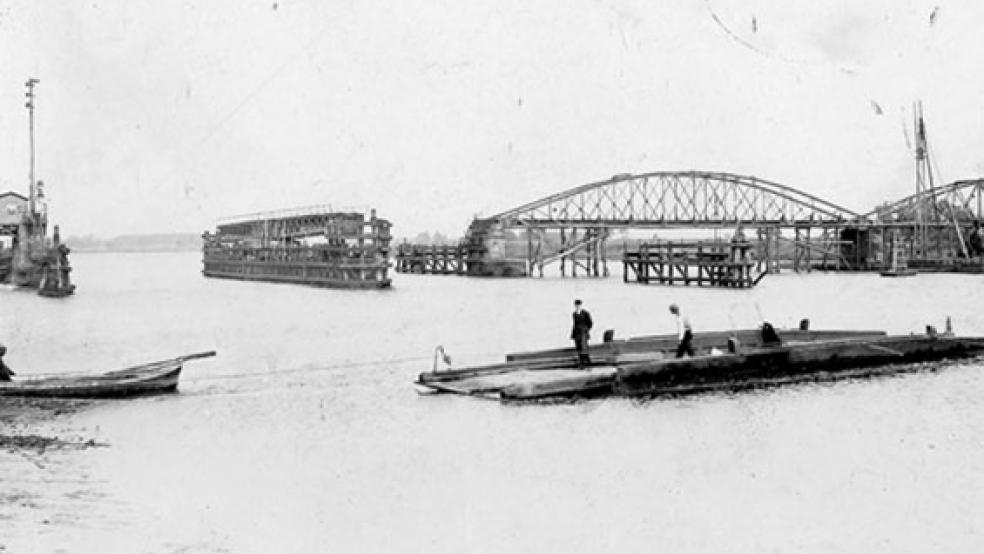 Diese historische Aufnahme zeigt im Hintergrund den Bau der ersten Friesenbrücke, die von 1874 bis 1876 als Drehbrücke errichtet wurde. Im Vordergrund ist die Fähre zu sehen, die zwischen Weener und Hilkenborg tagsüber im Viertelstundentakt und nachts bei Bedarf verkehrte. Der Fährpächter kassierte einmal jährlich den sogenannten Fährschatz von den Einwohnern. Dafür konnte man sich kostenlos übersetzen lassen. © Foto: Bernhard H. Meyer (www.sowasdat.rheiderland.de)