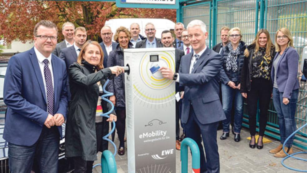 Landrat Matthias Groote (vorne rechts) zeigte, wie das Tanken an einer Stromtankstelle funktioniert. Zu dem Pressetermin kamen auch Vertreter der Kommunen und der EWE, die den Zuschlag für die Aufstellung erhalten hat. Aus dem Rheiderland waren Jemgums Bürgermeister Hans-Peter Heikens und Trinette Hoffbuhr von der Stadt Weener vor Ort. © Foto: Muising