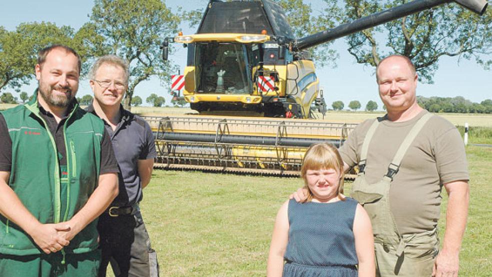 Vor einem Mähdrescher auf dem Hof von Peter Smith (rechts im Bild mit seiner siebenjährigen Tochter Nike) warben (von links) der Vorsitzende Georg Penon und Vorstandsmitglied Henrik Steenblock vom Landwirtschaftlichen Zweigverein Rheiderländer Marsch gestern für ihr »Co-Pilot«-Projekt, mit dem sie Kindern und Erwachsenen die Arbeit bei der Getreideernte näher bringen wollen. © Foto: Szyska