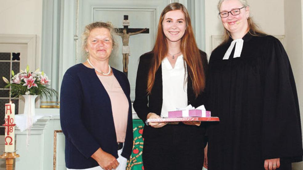 Die 18-jährige Eva Steinbach aus der Kirchengemeinde Jherings-/Boekzetelerfehn ist die jüngste Lektorin innerhalb der hannoverschen Landeskirche. Nach ihrer Amtseinführung nahmen Pastorin Imke Metz und Kirchenvorsteherin Heepke Bockelmann sie in die Mitte.  © Foto: Dübbel