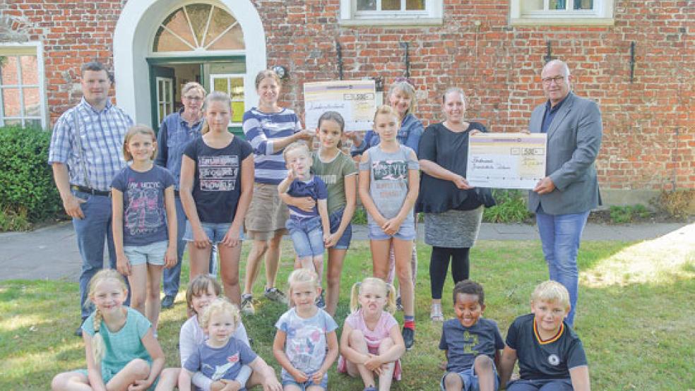 Das Foto zeigt einige der beteiligten Kinder sowie (von links) Gerjet Bültjer von der Mai- baum-Initiative, Jutta Troff und Sonja Dreesman vom Kindergottesdienst, Carola Bruhns, Antoinette Schnoig-van der Zijl vom Förderverein und Bürgermeister Hans-Peter Heikens vor dem Ditzumer Gemeindehaus.  © Foto: Himstedt