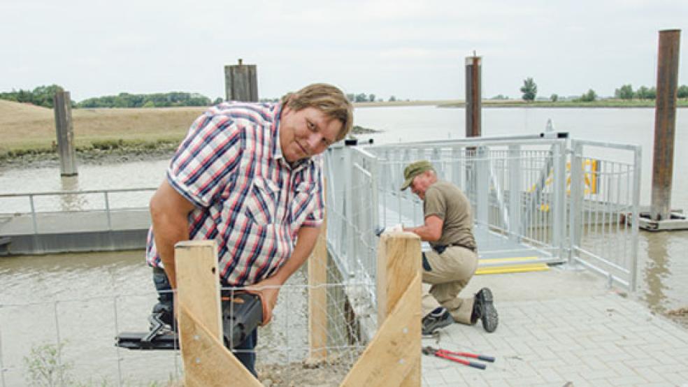 Auch gestern wurde am Fähranleger in Weener noch gearbeitet: Harald Wemjes, Chef des gleichnamigen Familienbetriebs aus Friesoythe, installierte mit einem Mitarbeiter einen Schutzzaun um den Zugang zum Fähr-Ponton. © Foto: Hanken