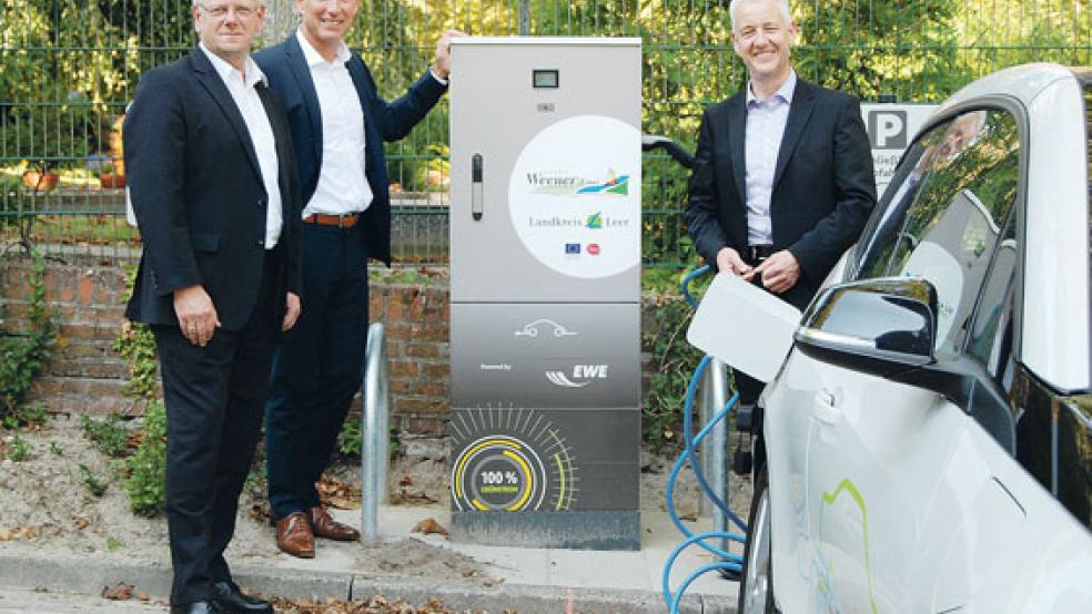 Eine Ladesäule für Elektroautos nahmen Bürgermeister Ludwig Sonnenberg, EWE-Vorstand Michael Heidkamp und Landrat Matthias Groote (von links) gestern auf dem Parkplatz des Rathauses offiziell in Betrieb.  © Foto: Hoegen