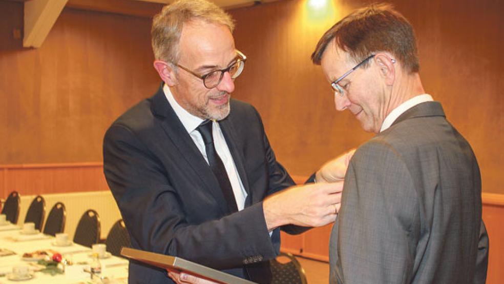 Axel Schwengels, Verbandsdirektor des Genossenschaftverbandes Weser-Ems, steckt Willem Berlin (rechts) die Silberne Ehrennadel des Genossenschaftsverbandes an. © Foto: Sabine Aey
