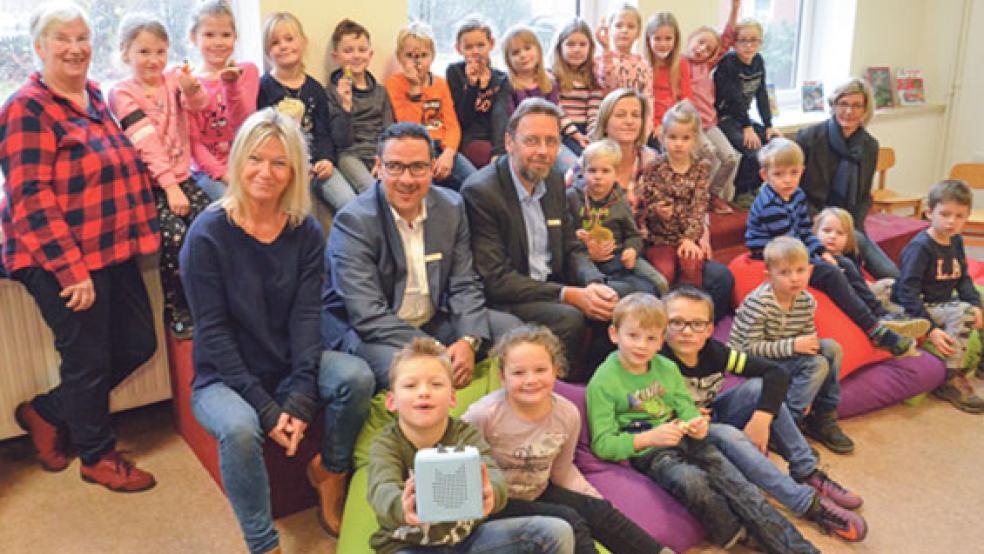 Mit den Kindern aus der Grundschule und dem Kindergarten freuten sich (von links) Bücherei-Leiterin Susanne Fockens, Direktorin Mechthild Tammena, Hermann Hantschel und Alfred Lüppens von der Sparkasse, Nebenstellen-Leiterin Silke Freese und Ingrid Sonnenberg (Leiterin Kindergarten) über die neue Toniebox (kleines Bild).  © Foto: Muising