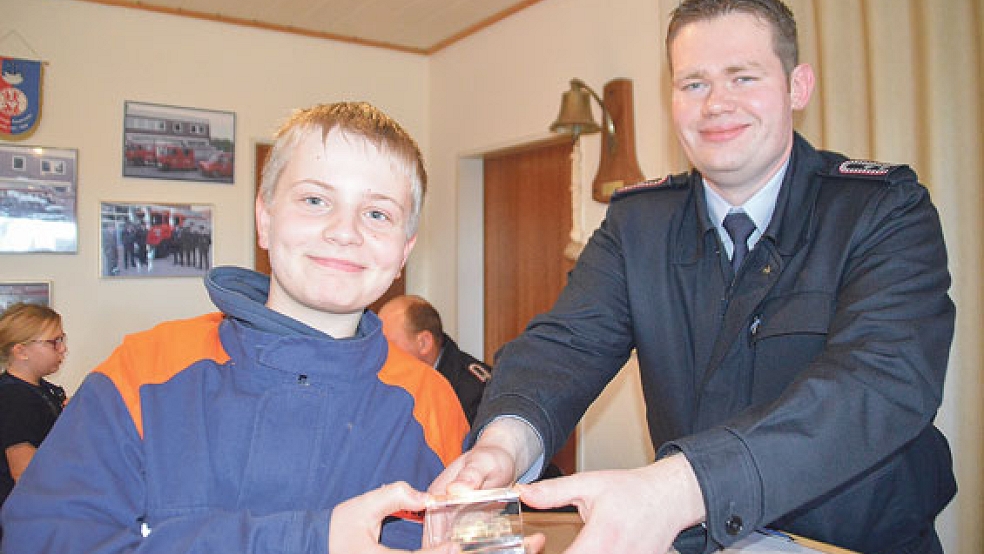 Finn Jürgens ist »Jugendfeuerwehrmann des Jahres« und bekam als Anerkennung von Betreuer Arno Yzer ein gläsernes Feuerwehrauto geschenkt. © Foto: Himstedt
