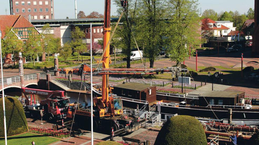 Hoch in der Luft schwebt ein Teil der Masten der Brigg Friederike. Gestern haben die Aufbauarbeiten auf dem Schiff vor dem Rathaus begonnen. Bis zum Ende nächster Woche soll die Friederike wieder komplett sein. © Foto: Stadtverwaltung Papenburg