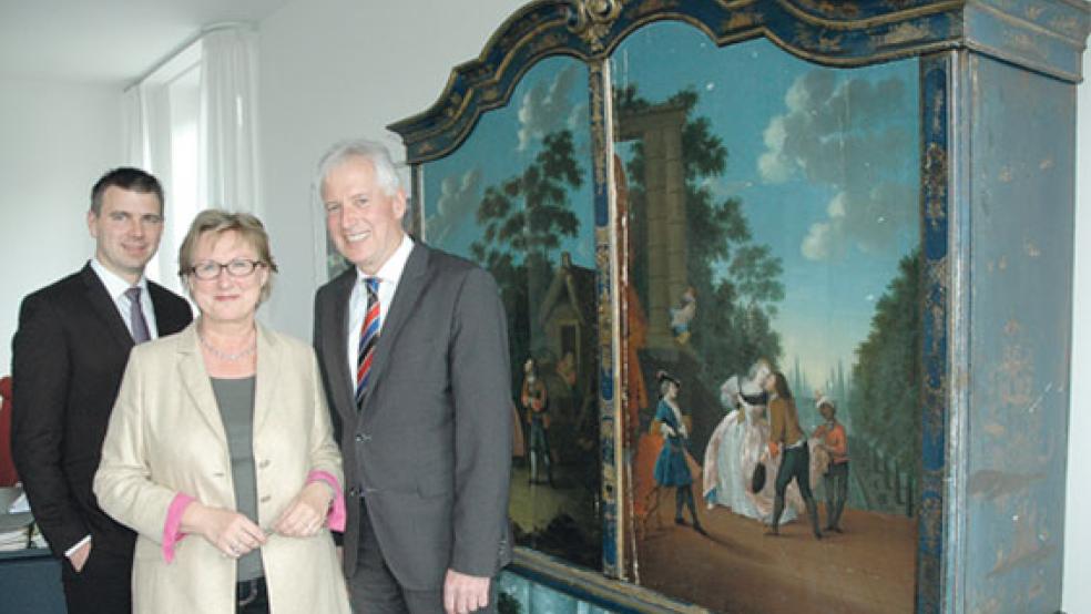 Ein Blickfang aus dem Rheiderland schmückt das Büro des Vorstandsvorsitzenden Thomas Weiss (rechts). Der ostfriesische Kabinettschrank aus dem 18. Jahrhundert stammt aus der Bunder Gegend und wurde von einem Wandermaler aufwändig verziert. Weiss präsentierte gestern in Aurich zusammen mit seinem Vorstandskollegen Gerrit Wilken und Pressesprecherin Signe Foetzki das vorläufige Geschäftsjahresergebnis 2018 der Ostfriesischen Landschaftlichen Brandkasse. © Foto: Szyska
