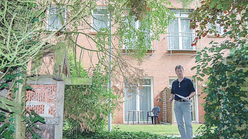 An das Gebäude im Hintergrund soll der Anbau »angesetzt« werden, Geschäftsführer Andreas Cramer steht in dem Gartenbereich, der überbaut werden soll. © Foto: Hoegen
