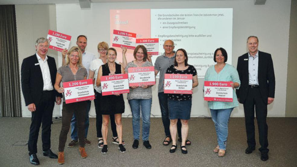 Heinz Feldmann und Carsten Rinne (links und rechts, beide Sparkasse) überreichten die Schecks an die Vertreter der Rheiderländer Schulen (von links): Mechthild Tammena (Grundschule Möhlenwarf), Thomas Stern (GS Wymeer), Britta Worpenberg (GS Jemgum), Gabi Gödecke (GS Stapelmoor), Britta Borgmann (GS Ditzum), Gerrit Wille (GS Bingum), Sandra Adler (GS Dollart) und Anja Meißner (GS Weener). © Foto: Wolters