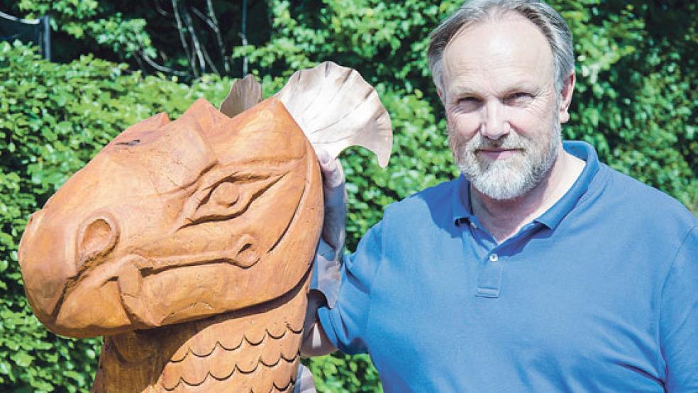 Schnitzer und Schreiber: Krimi-Autor Wolfgang Santjer mit einer Drachenfigur aus seiner Werkstatt, die nun den Garten seines Heimes in Bingum ziert. © Foto: Hanken