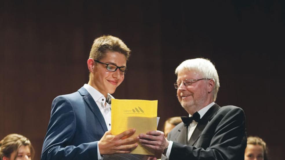Oberstufenkoordinator Erich Veddeler, der diesen Jahrgang zum letzten Mal vor seinem Ruhestand zum erfolgreichen Abitur führte, überreicht dem Jahrgangsbesten Mischa Lau- terbach aus Leer den Geographiepreis für das beste Abitur im Fach Erdkunde. © Fotos: UEG