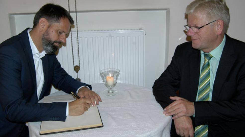 Minister Olaf Lies trug sich auf Bitte von Bürgermeister Ludwig Sonnenberg (rechts) ins Gästebuch der Stadt ein. © Foto: Hoegen