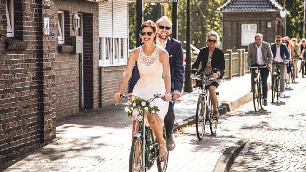 Nach der Trauung über die Rathausbrücke am Hafen: Stephanie Hilde Heselmeyer, geborene Schouwer, und Jan Heselmeyer führen als Frischvermählte auf einem Tandem den Rad-Korso der Hochzeitsgesellschaft an. © Foto: Benjamin Luikenga