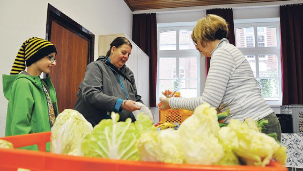 Im Gemeindehaus der ev.-ref. Kirche in Jemgum werden die Lebensmittel ausgegeben. Als ehrenamtliche Helferin packt auch Elka Hensmann (rechts) mit an.  © Foto: Boelmann