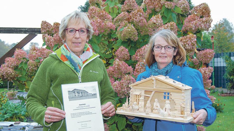 Diese handgeschnitzte Krippe, die Geziena Scholtalbers in den Händen hält, gibt es bei einer der beiden Verlosungen während der Ausstellung in der Möhlenwarfer Grundschule zu gewinnen. Links Jeane Schmidt mit einem Tagesfahrt-Gutschein. © Foto: Hoegen