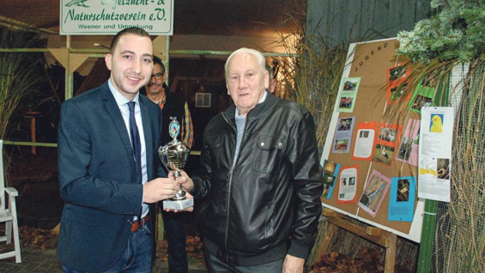 Der stellvertretende Bürgermeister Nico Bloem (links) überreichte Bernhard Bartels den Bürgermeister-Pokal der Stadt Weener für die schönste Voliere; im Hintergrund der Vereinsvorsitzende Rudolf Schaa. © Fotos: Kuper