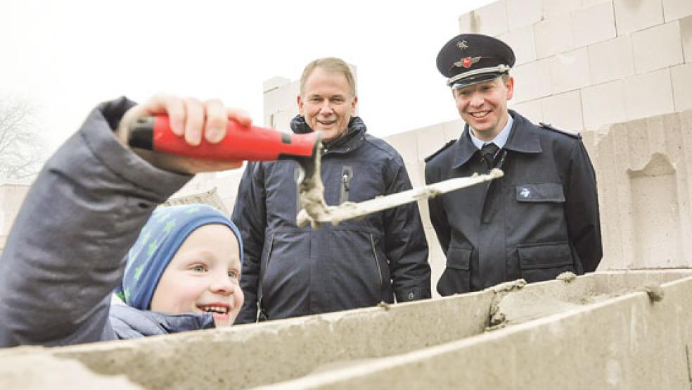 Unter den Blicken von Ortsbrandmeister Thomas Kempen (rechts)und Bundes Bürgermeister Gerald Sap durfte auch Julius, er ist in der Kinderfeuerwehr in Jemgum aktiv und der Sohn vom Ortsbrandmeister, bei der Grundsteinlegung zur Kelle greifen. © Fotos: Boelmann