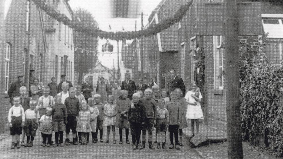 Die historische Aufnahme zeigt die geschmückte Sielstraße in Jemgum mit zahlreichen Kindern und Anwohnern. Die jüdische Familie Cohen wohnte dort gegenüber der Kohlenhandlung von Enno Meyer, in der heute das Milch- und Molkereimuseum beheimatet ist. Inzwischen erfolgte eine Umbenennung in »Marktstraße«, auch die Hausnummern haben sich geändert. Cohens Wohnhaus stand etwa dort, wo sich heute der Parkplatz des Seniorenheims »Auf der Wierde« befindet. © Foto: Sammlung Baartz (www.sowasdat.rheiderland.de)