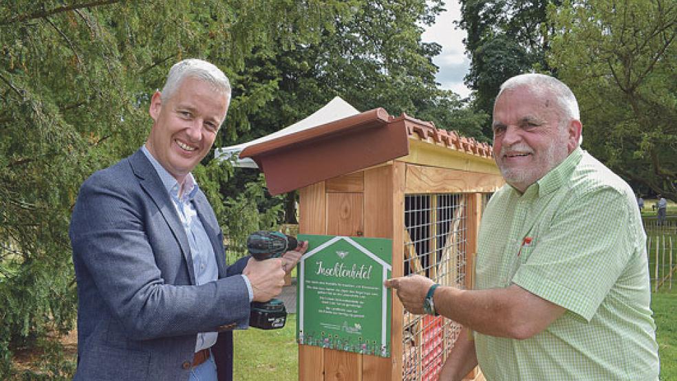 Landrat Matthias Groote (links) und der Vorsitzende des Hegerings Leer, Reinhard Leising aus Weener, brachten gemeinsam ein Schild an, welches auf ein neues Insektenhotel hinweisen soll. © Foto: Landkreis Leer