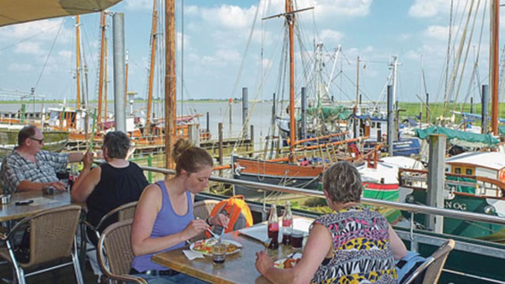 Touristen genießen auf der Terrasse des »Fischhaus Ditzum« den Blick auf Hafen und Ems. © Foto: Ostfriesland Tourismus GmbH