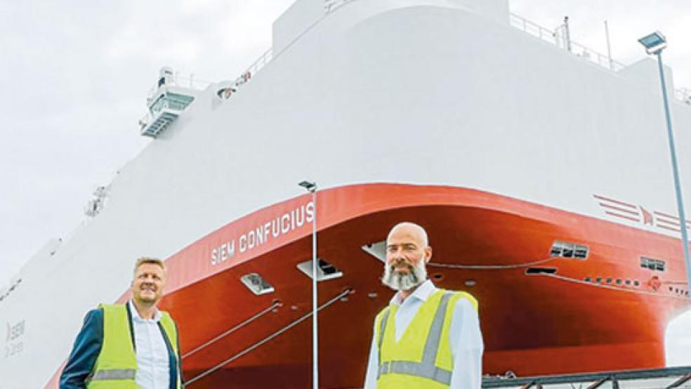 Begrüßten den neuen Dauergast: VW-Verladekapitän Torben Stadtaus (rechts) und VW-Logistikmanager Manfred de Vries vor der ausschließlich mit Flüssiggas betriebenen »Siem Confucius« am neuen Emskai. © Foto: Hasseler