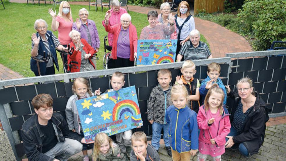 Bei der Zaunübergabe des Bildes: Hinter dem Zaun Bewohner und Betreuungskräfte des Altenzentrums. Vor dem Zaun die Kinder der »Bunten Welt« mit ihren Betreuern. Beide halten ihr Bild in den Händen. © Foto: privat