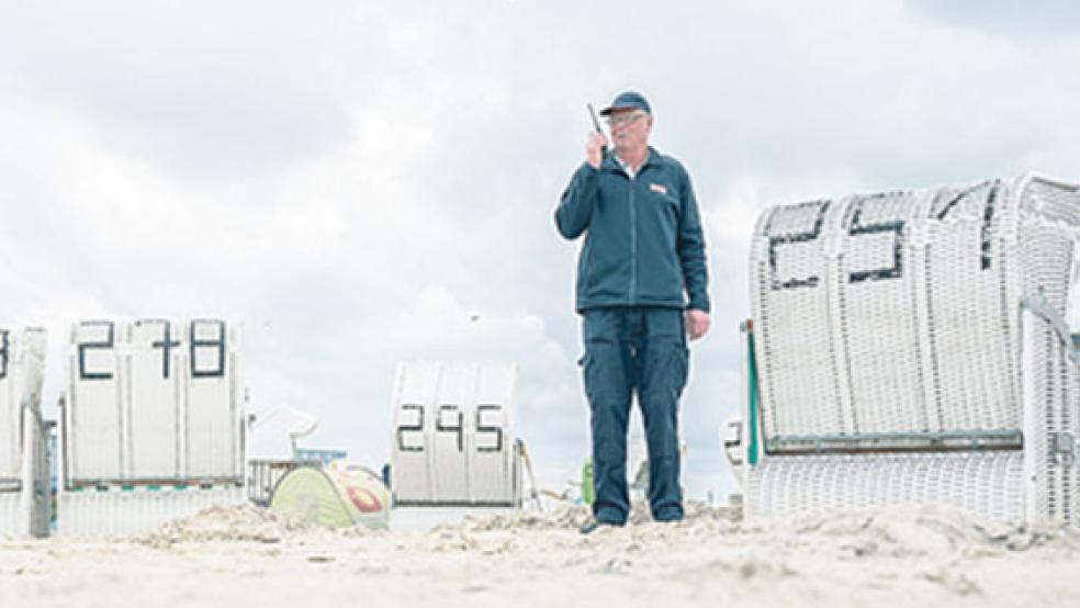 Am Badestrand von Norddeich spricht Georg Ulrichs, Sicherheitskraft der WSB-Sicherheitsdienst GmbH, während seines Kontrollrundgangs über ein Funkgerät mit einem Kollegen. © Foto:Assanimoghaddam/dpa