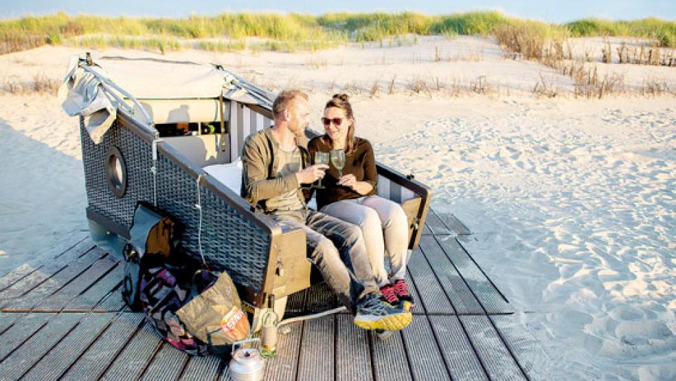 Elli und Sascha aus Bremen sitzen am Strandabschnitt »Weiße Düne« auf Norderney in ihrem gebuchten Schlafstrandkorb und genießen die Abendsonne. In den Strandkörben können Urlauber eine Nacht unter dem Sternenhimmel genießen.  © Foto: Hauke-Christian Dittrich/dpa
