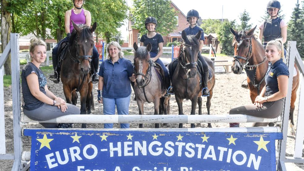 Alice Smidt (links), Silke Smidt-Ligmann (stehend) und ihre Tochter Hanna Ligmann (rechts) sind drei Ausbilder im Reitstall. Im Hintergrund die Nachwuchsreiter. © Foto: Bruins