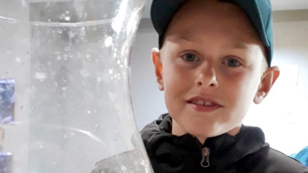 Der neunjährige Aike betrachtet ein seltenes Seepferdchen, das er beim Keschern im Borkumer Hafen gefangen hat. © privat/dpa