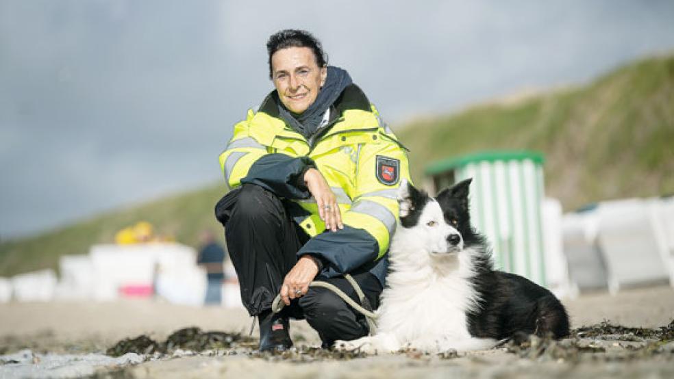 Kriminaloberkommissarin Heike Cleve steht mit ihrem Hund »Split« am Strand von Baltrum. Früher ermittelte die Polizistin in einer Großstadt Morde oder Sexualdelikte, heute geht sie auf der kleinsten der Ostfriesischen Inseln auf Streife.  © Foto: Schuldt (dpa)