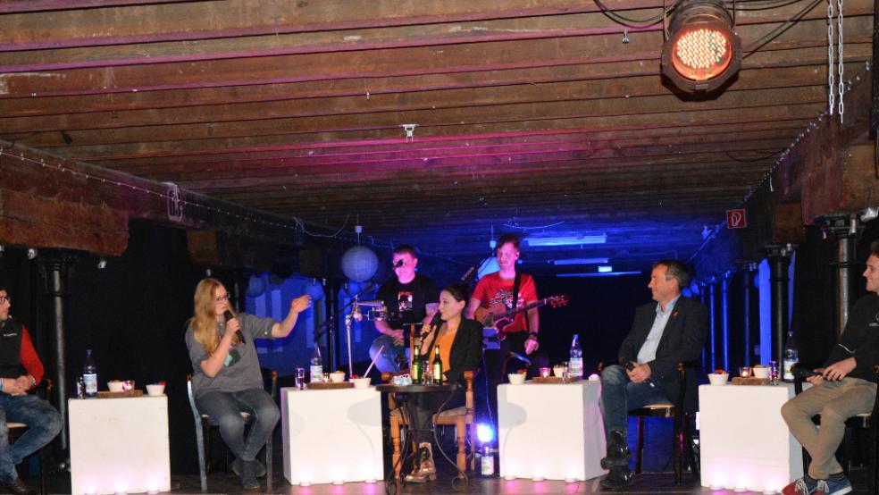 Auf Plattdeutsch unterwegs: Timo Hommers, Neele Gruis, Moderatorin Annie Heger, Johann Saathoff und Dieke Günther (im Bild von links) beim »Klönschnack« auf der Bühne im Leeraner Zollhaus. Im Hintergrund Chris Lawatsch und Andy Siefkes vom »Duo Infernale«. © Foto: Eden