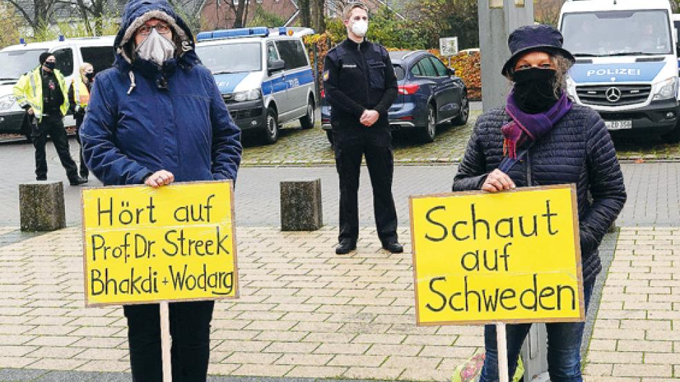 Mit Maske und Transparenten sind diese beiden Demonstranten angetreten. Die Auricher Polizei war während der Kundgebung präsent. © Foto: Otto