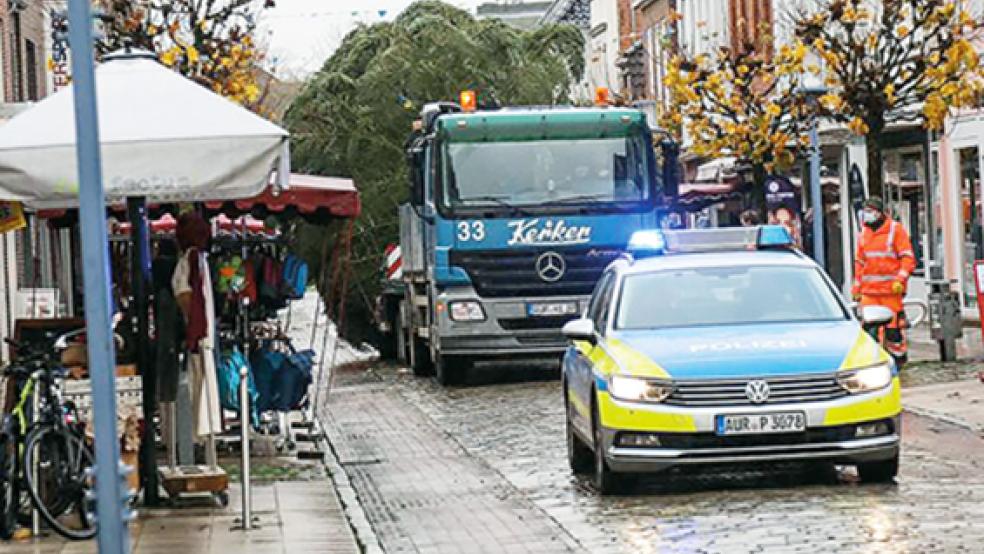 Begleitet von der Polizei fährt der Sattelzug mit der 15 Meter hohen Nordmanntanne durch die Norderstraße in Aurich.  © Foto: Banik