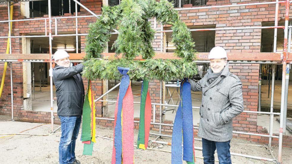 Auch die letzte Schleife sitzt: (von links) Technischer Leiter Tobias Fiedelak und Geschäftsführer Dieter Brünink (von links) beim Schmücken der Richtkrone. © Foto: Henschel/Borromäus Hospital