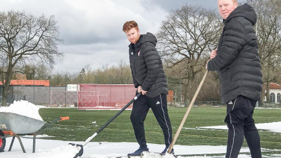 Erst muss der Schnee vom Platz: Hendrik Poppinga und Thorben Cordes vom Trainerteam packten selbst mit an. © Foto: privat