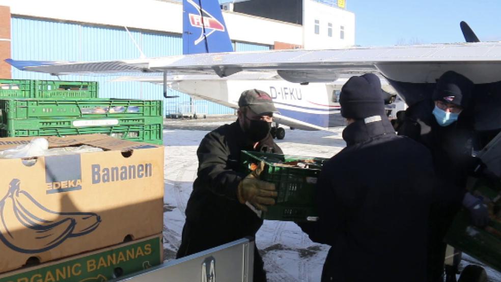 Helfer laden Obst und Gemüse aus Flugzeugen nach deren Landung auf dem Flughafen auf der Insel Wangerooge. Seit Montag vergangener Woche fuhren wegen Eis und Niedrigwasser keine Fähren mehr. Frische Lebensmittel wie Obst, Gemüse, Milch und Eier wurden deshalb mit dem Flugzeug geliefert. Nun entspannt sich die Situation. © Foto: Kuchenbuch-Hanken (dpa)