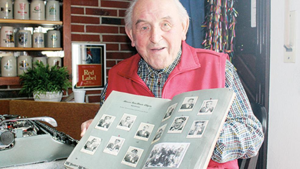Albert Schmidt mit seinem Heimatsportbilder-Sammelalbum. Zu sehen ist die Vereinsseite mit den Spielern des MTV Ditzum und ihren »Haarteilen«.  © Foto: Berents