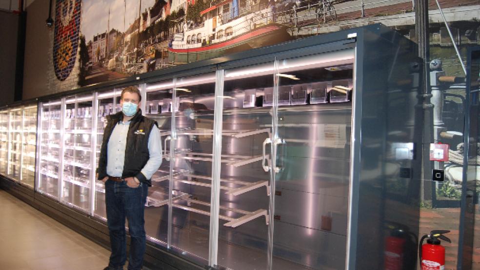 Das Wappen der Stadt Weener und eine große Fototapete mit einem Motiv aus dem Alten Hafen von Weener zieren die hintere Innenwand des neuen E-Centers von Edeka in Weener. Im Bild Marktleiter Tim Berge. © Hoegen