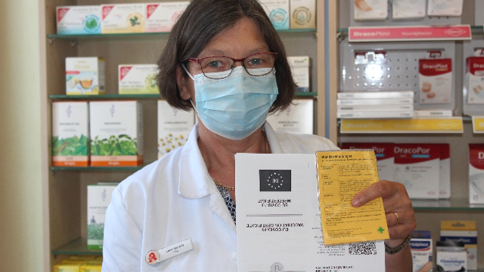 Luise Garrels von der Adler Apotheke in Bunde, hält einen Corona-Impfnachweis und einen Impfpass. Diese müssen zusammen mit einem Personalausweis vorgelegt werden, damit der Nachweis digitalisiert werden kann. © Berents
